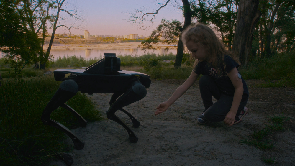 Still from Open World. Girl with a robotic dog in a natural setting.